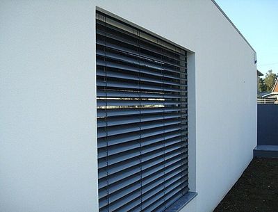 Estore exterior de lâminas orientáveis cinzentas numa janela de moradia moderna branca