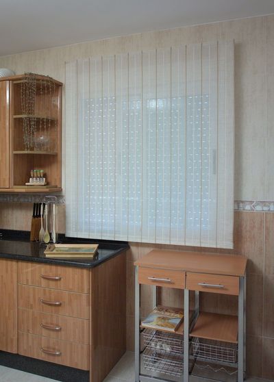 Estore interior de fibra natural translúcido numa cozinha com armários de madeira