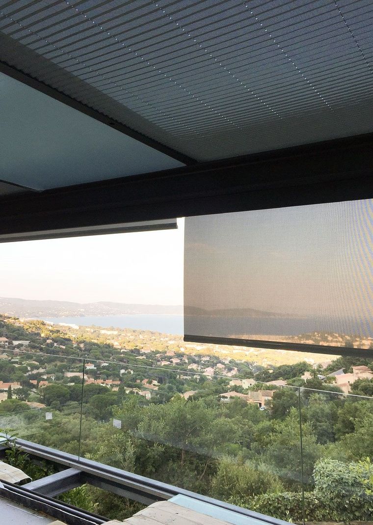 Estore exterior de rolo parcialmente descido sob pérgola, com vista panorâmica para a baía