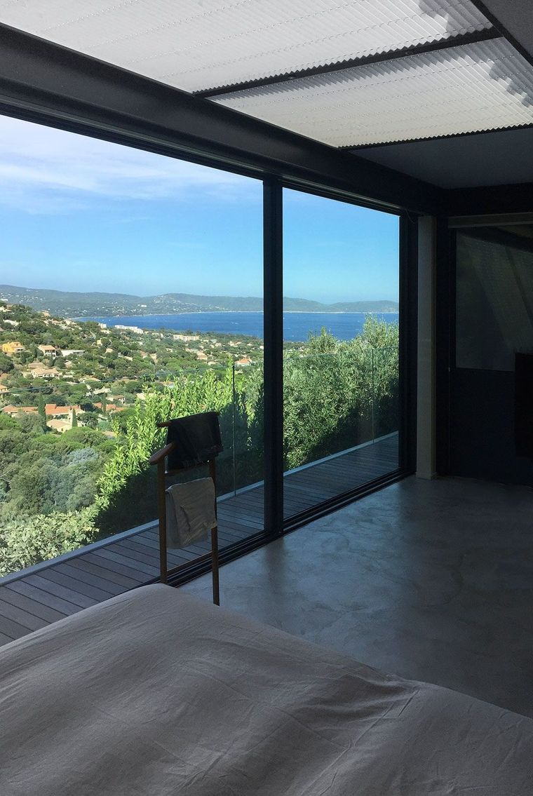 Estore plissado de teto recolhido num quarto envidraçado com vista panorâmica para a baía